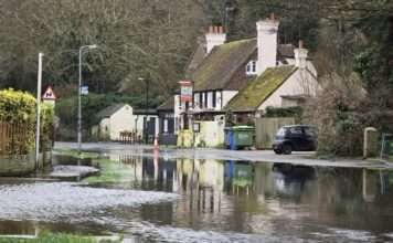 Despite improvements, the threat of re-flooding keeps Denton Road shut, impacting local life and businesses.